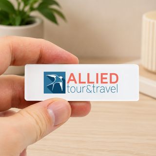 Hand holding a white acrylic name tag printed with a full colour company logo