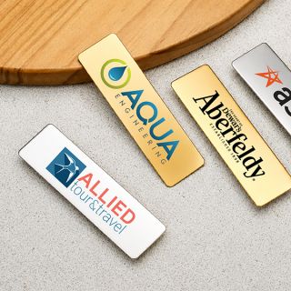 Gold, silver and blue metal name tags laid out on a wooden board
