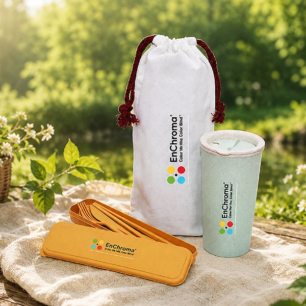 White drawstring pouch, mint tumbler and a cutlery set in a yellow case on a stone surface outdoors, each printed with a logo