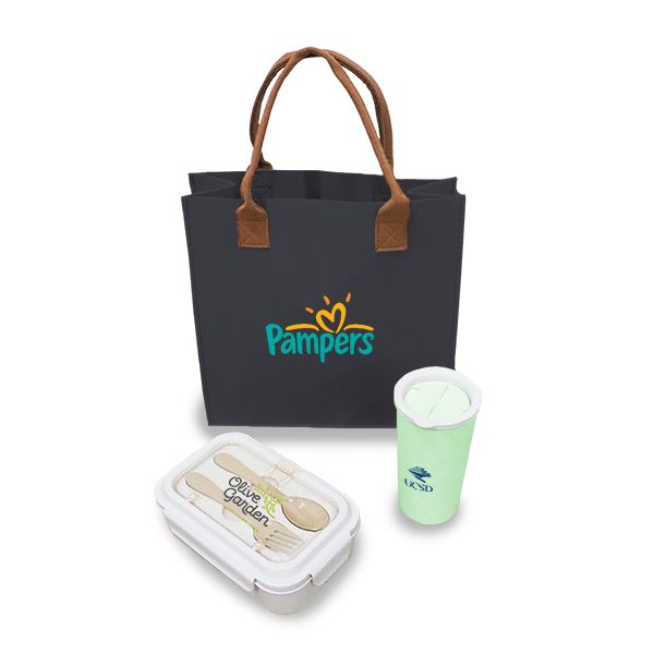 Black tote bag with brown handles beside a glass lunch box and a green tumbler, printed with a logo