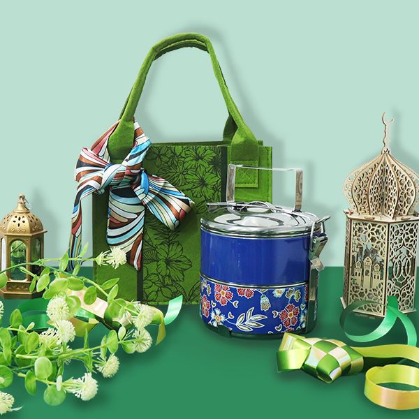 Green tote bag with a patterned scarf, a blue batik tiffin carrier and a lantern on a mint backdrop