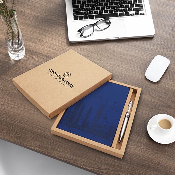 Kraft gift box open on a desk with a blue A5 notebook and a pen seated in the two compartments