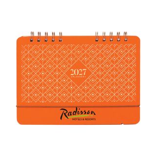Orange wire-o desk calendar standing upright, its cover in a diamond lattice pattern with a logo printed on the base panel.