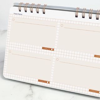 Project planner spread with four ruled boxes and rose gold tab labels on a pale grid page.