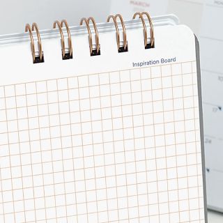 Inspiration board page in an orange grid, held open by the rose gold twin wire binding.