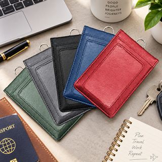 Green, black, navy and red magnetic PU ID holder wallets laid on a desk beside a passport, pen, keys and notebook
