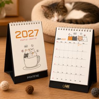 Two Meow Moments desk calendars on a desk, one closed at the cover and one open at a monthly page