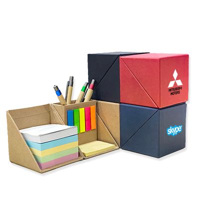 Eco cube memo notepads in kraft, red and navy, one open to show sticky notes and a pen holder, each printed with a logo