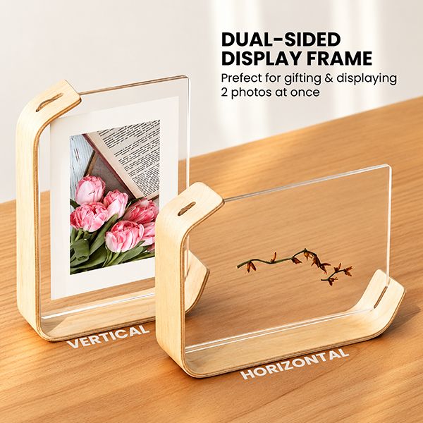 The double-sided acrylic photo frame shown upright with a photo and on its side with an engraved motif, both on light wood bases
