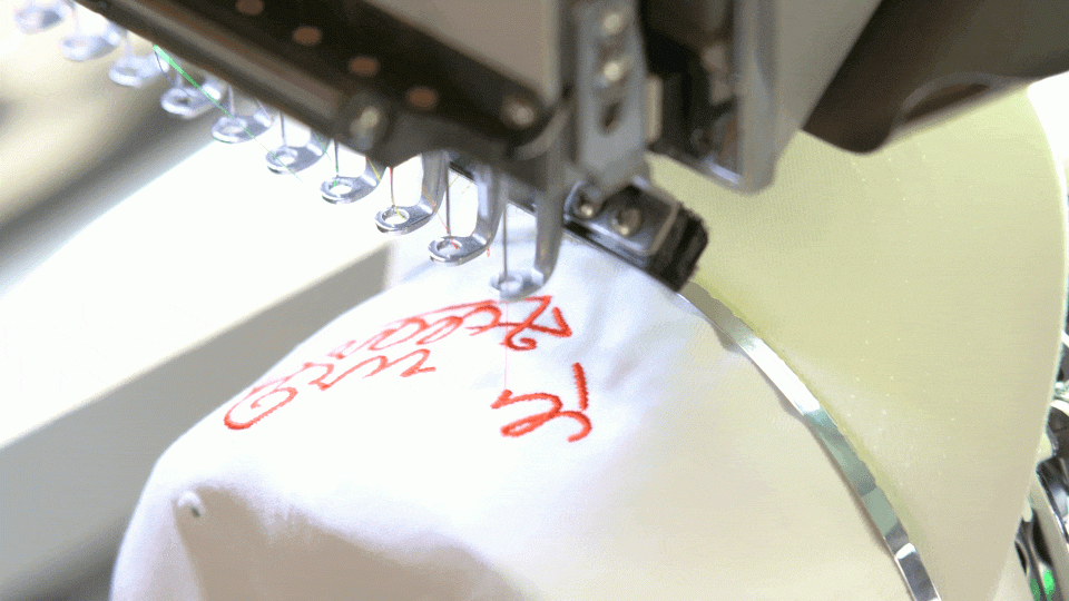 Embroidery machine stitching a logo onto a cap